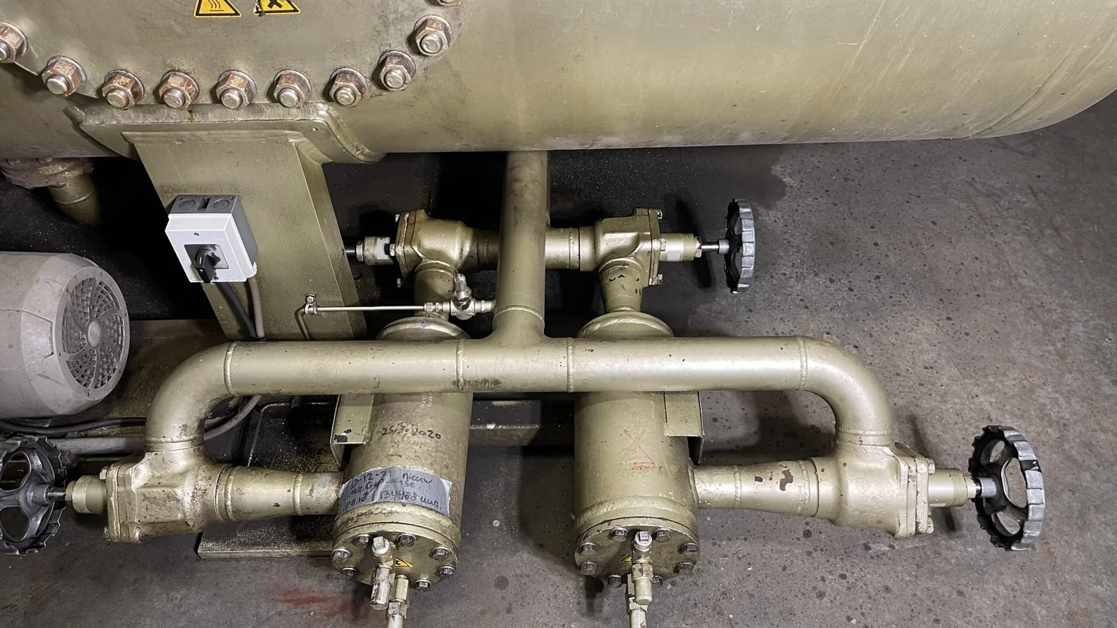 Leidingen met afsluiters onder een industriële tank